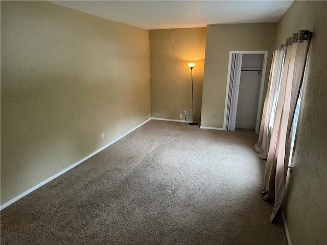 unfurnished bedroom featuring a textured wall, carpet floors, and baseboards