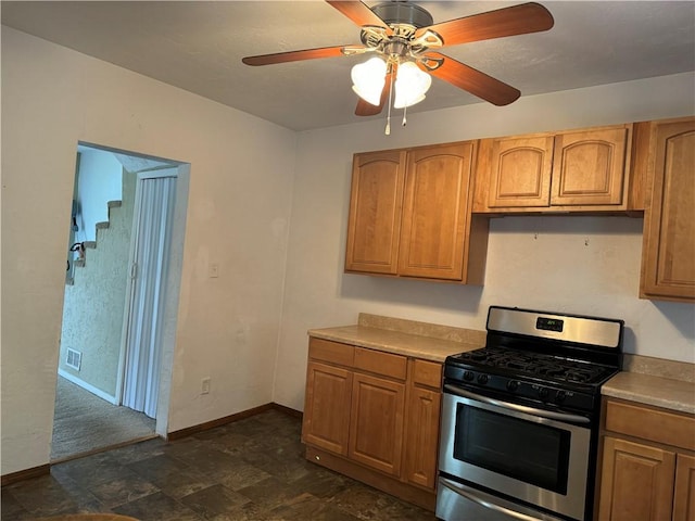 kitchen featuring stone finish flooring, baseboards, brown cabinets, and gas stove