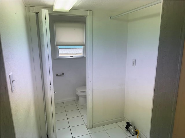 bathroom featuring toilet, tile patterned flooring, and baseboards