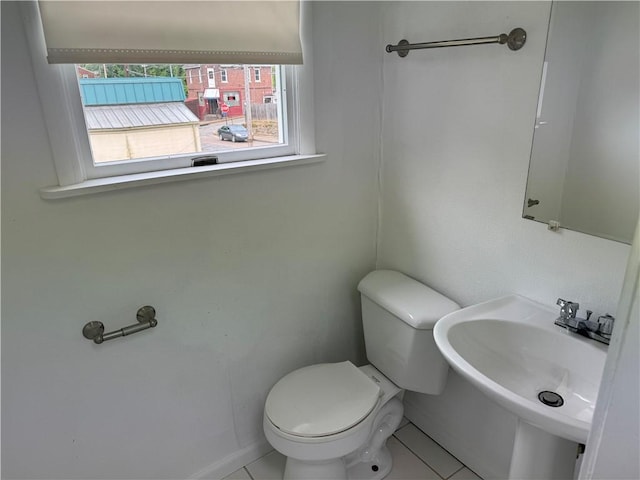 half bath with a sink, toilet, and tile patterned floors