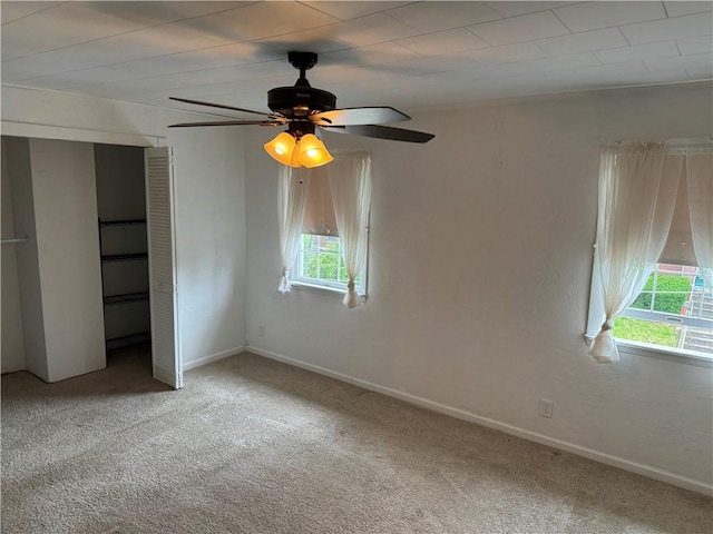 unfurnished bedroom with carpet floors, a closet, baseboards, and a ceiling fan