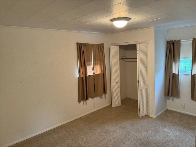 unfurnished bedroom with ornamental molding, carpet, a closet, and baseboards