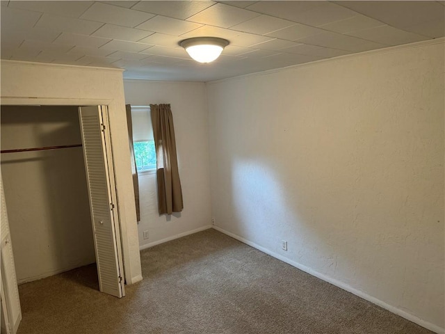 unfurnished bedroom with carpet floors, baseboards, a closet, and a textured wall