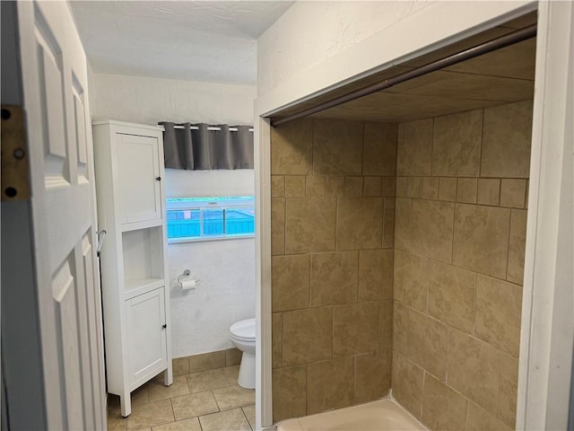 bathroom with a shower, tile patterned flooring, and toilet