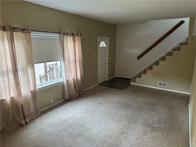 foyer entrance featuring carpet, visible vents, baseboards, and stairs