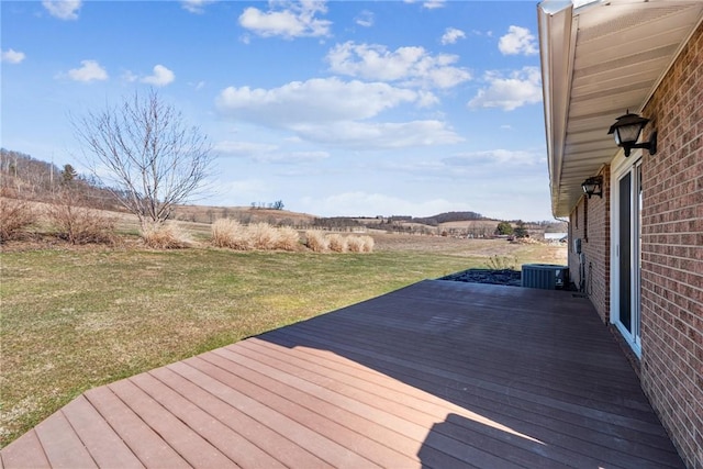 deck with cooling unit, a lawn, and a rural view