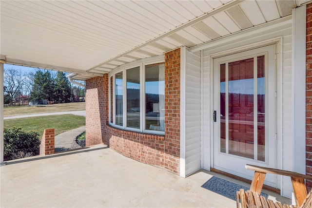 property entrance with brick siding and a patio area