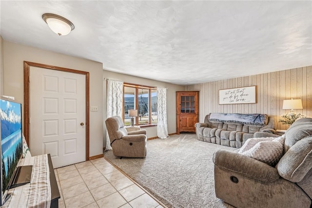 living area featuring baseboards, light tile patterned flooring, a textured ceiling, and light colored carpet