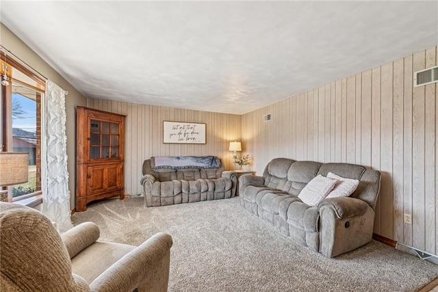 living area with visible vents, wood walls, and carpet flooring