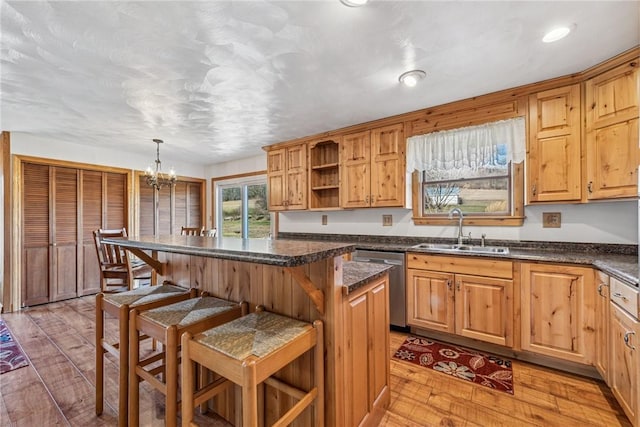 kitchen featuring a breakfast bar area, a kitchen island, a sink, dishwasher, and light wood finished floors