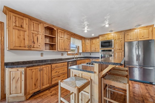 kitchen with light wood-type flooring, a kitchen bar, appliances with stainless steel finishes, and a sink