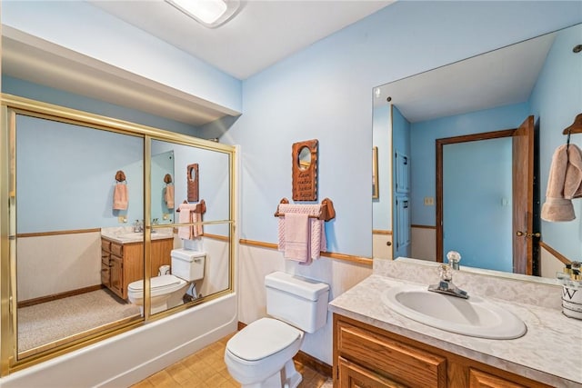 bathroom featuring enclosed tub / shower combo, vanity, and toilet