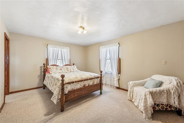 bedroom featuring multiple windows, light carpet, and baseboards