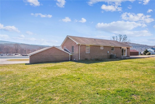 rear view of house with brick siding, a lawn, and central air condition unit