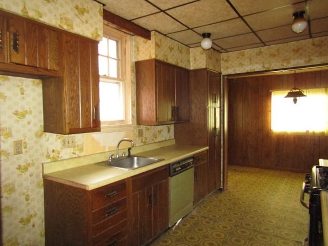 kitchen featuring wallpapered walls, dishwasher, light countertops, a sink, and gas stove