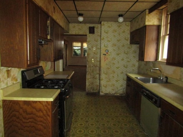 kitchen featuring a paneled ceiling, a sink, light countertops, dishwasher, and stainless steel range with gas stovetop