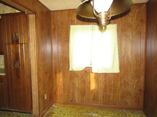 empty room featuring wooden walls and baseboards