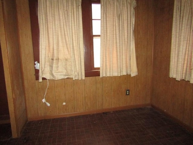 empty room featuring wood walls and baseboards