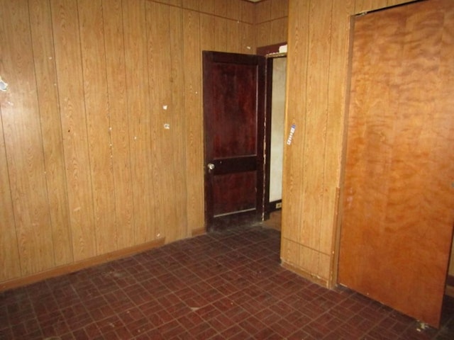 unfurnished room with brick floor and wood walls