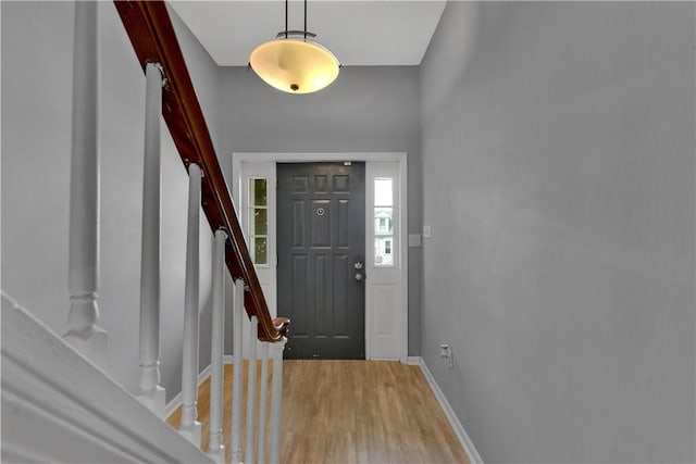 entrance foyer featuring stairway, light wood-type flooring, and baseboards