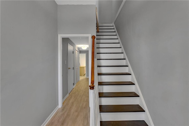 staircase featuring wood finished floors and baseboards