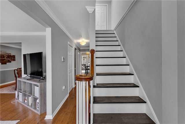 stairway featuring ornamental molding, baseboards, and wood finished floors