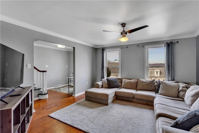 living area with baseboards, ceiling fan, stairway, ornamental molding, and wood finished floors