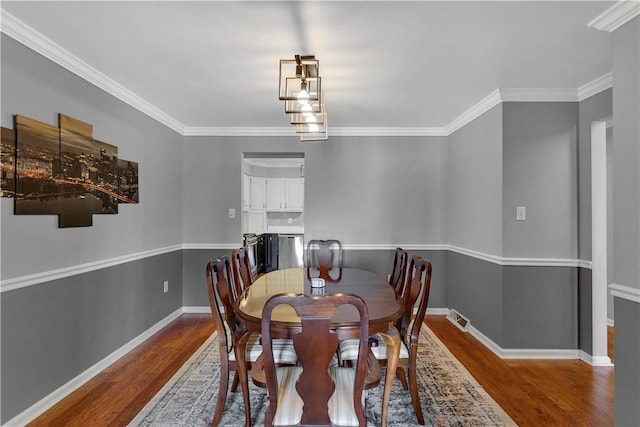 dining area featuring ornamental molding, visible vents, baseboards, and wood finished floors