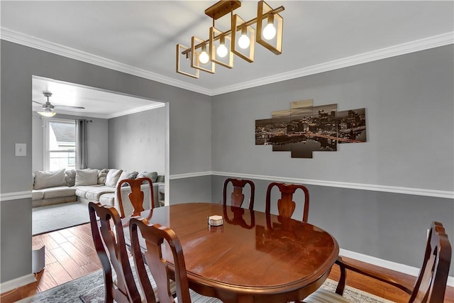 dining area with baseboards, ceiling fan with notable chandelier, wood finished floors, and crown molding