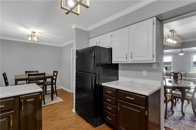 kitchen with light wood-style floors, white cabinets, crown molding, and freestanding refrigerator