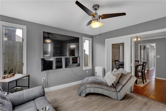 living area with ceiling fan, radiator, wood finished floors, and baseboards