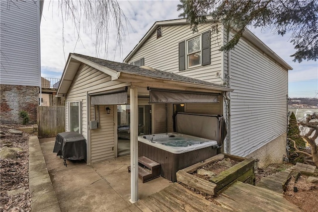 view of property exterior with a patio, a hot tub, and fence