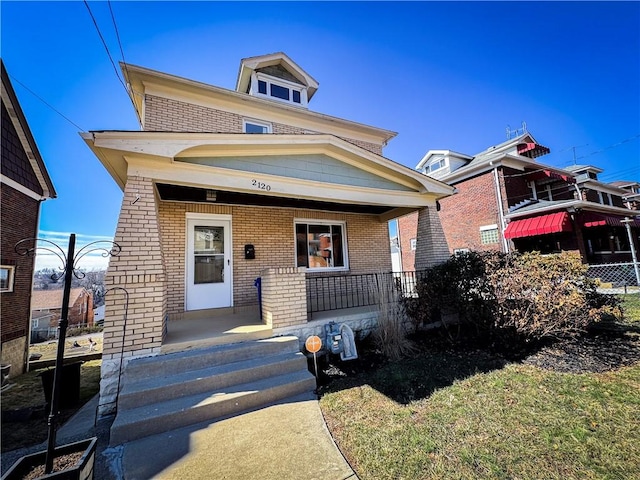 american foursquare style home featuring a porch and brick siding