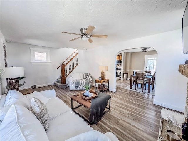 living room with baseboards, visible vents, arched walkways, wood finished floors, and stairs