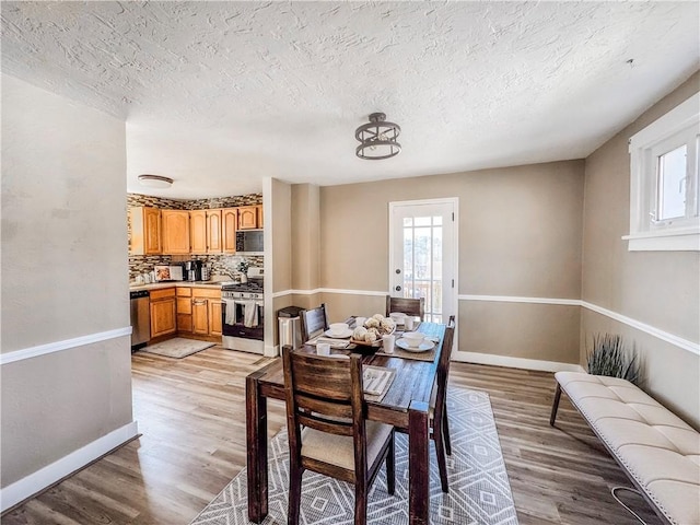 dining space featuring light wood-style floors, baseboards, and a wealth of natural light