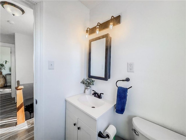 half bathroom with wood finished floors, vanity, and toilet