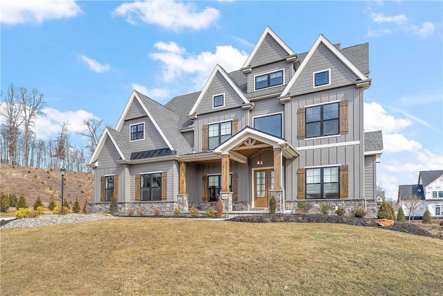 view of front of home with stone siding, a standing seam roof, board and batten siding, and a front yard