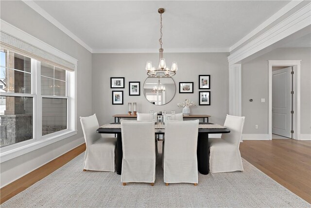 dining space with a notable chandelier, baseboards, wood finished floors, and crown molding