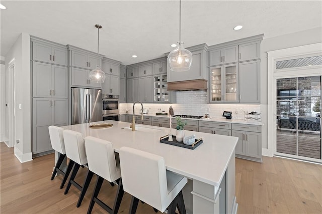 kitchen featuring appliances with stainless steel finishes, a sink, gray cabinetry, and a kitchen bar