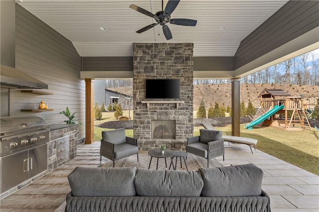 view of patio / terrace with exterior kitchen, a playground, grilling area, and an outdoor living space with a fireplace