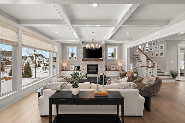 living area with stairway, coffered ceiling, wood finished floors, and a stone fireplace