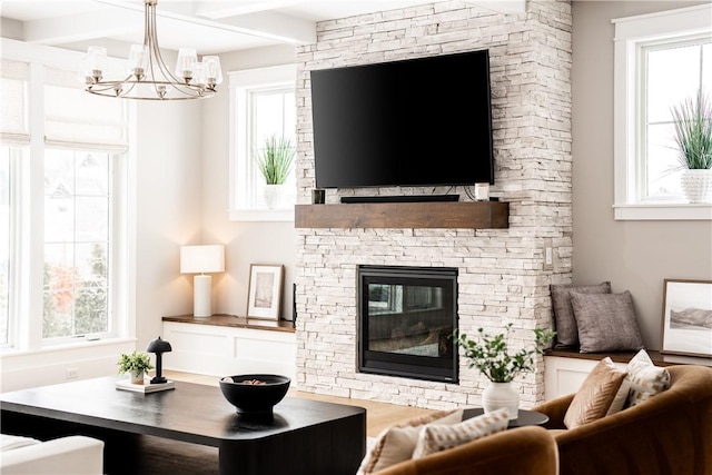 living room with a chandelier, beamed ceiling, a fireplace, and wood finished floors