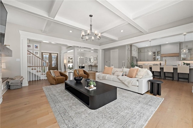 living area with coffered ceiling, beamed ceiling, light wood-style flooring, and an inviting chandelier