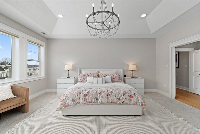 carpeted bedroom with a notable chandelier, a tray ceiling, visible vents, and baseboards