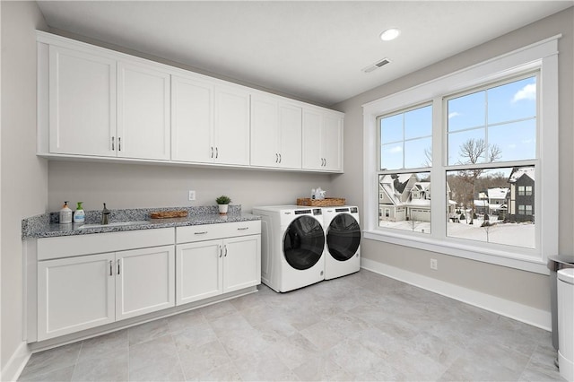 laundry area with washing machine and dryer, a sink, visible vents, baseboards, and cabinet space