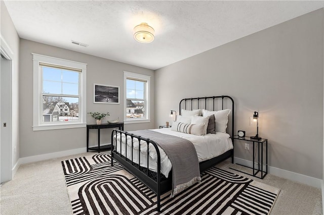 bedroom with a textured ceiling, carpet floors, visible vents, and baseboards