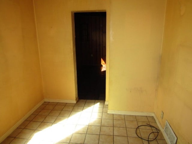 tiled empty room with baseboards and visible vents