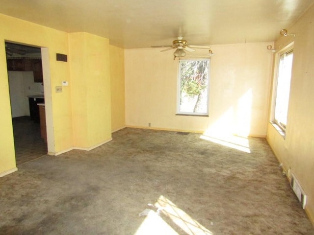 carpeted empty room with a ceiling fan, visible vents, and a healthy amount of sunlight