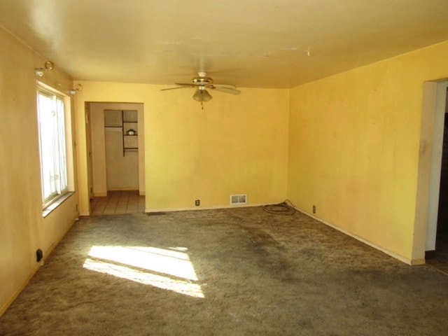 empty room with ceiling fan, carpet flooring, and visible vents