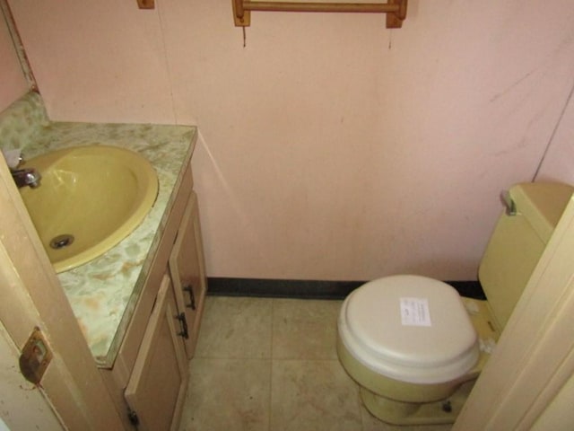 half bath featuring toilet, tile patterned floors, baseboards, and vanity